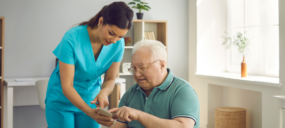 A healthcare worker assists a patient with a cell phone in a bright clinic room.